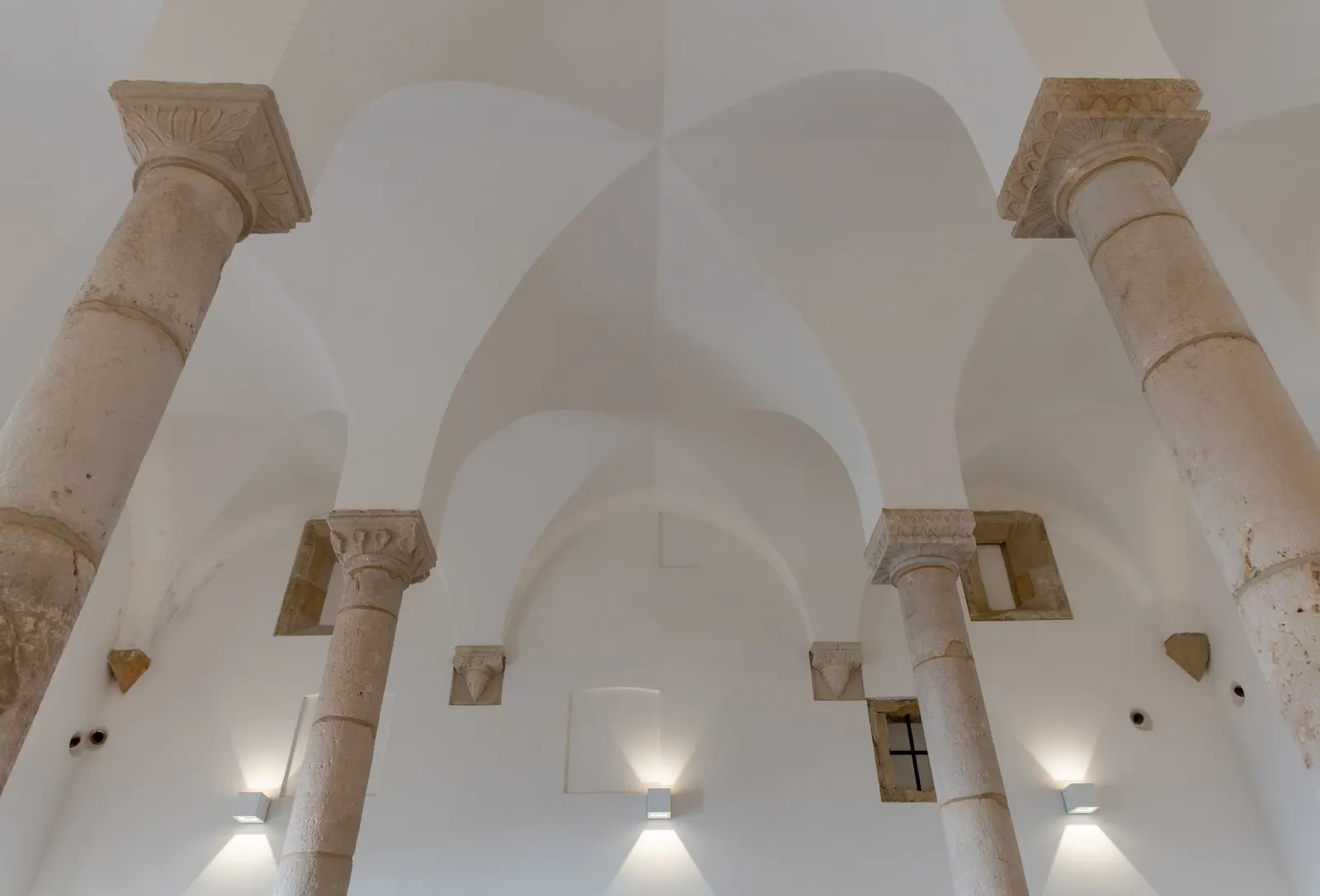 Quatre colonnes en pierre, chapiteaux sculptés et voûtes blanches à l’intérieur de la synagogue de Tomar